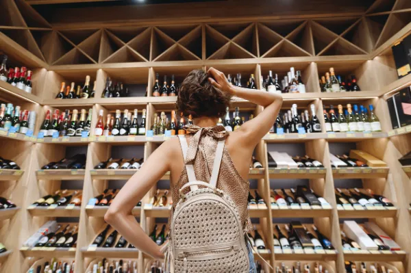 Puzzled young woman choosing wine