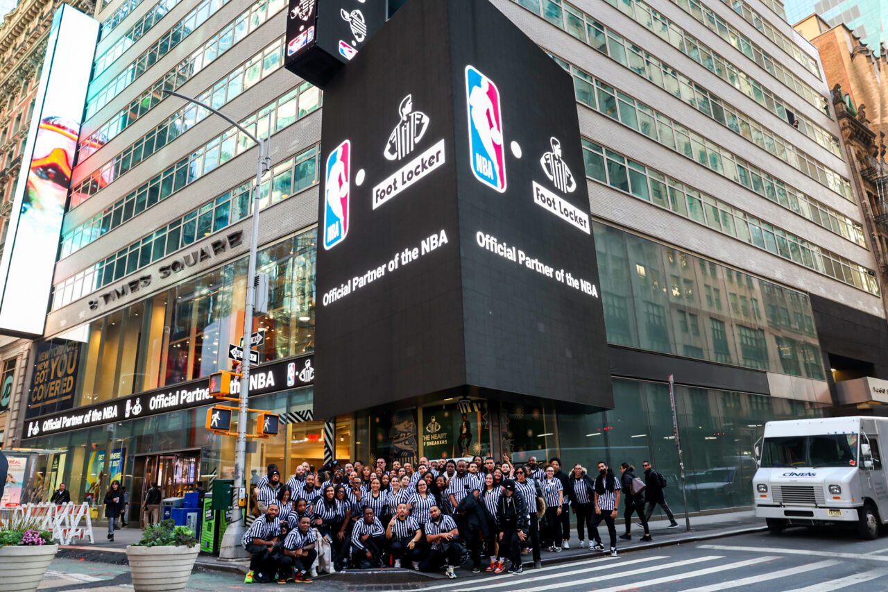 Foot Locker employees with a Times Square ad touting the company's partnership with the NBA. 
